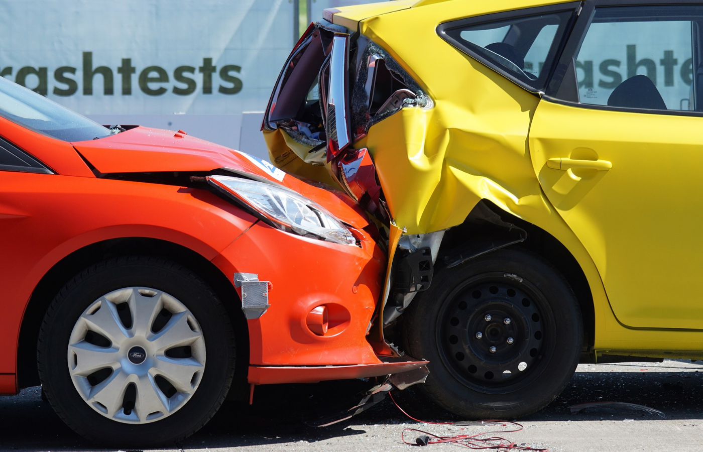 An orange car in a front-end collision with the rear-end of a yellow hatchback during a crash test evaluation